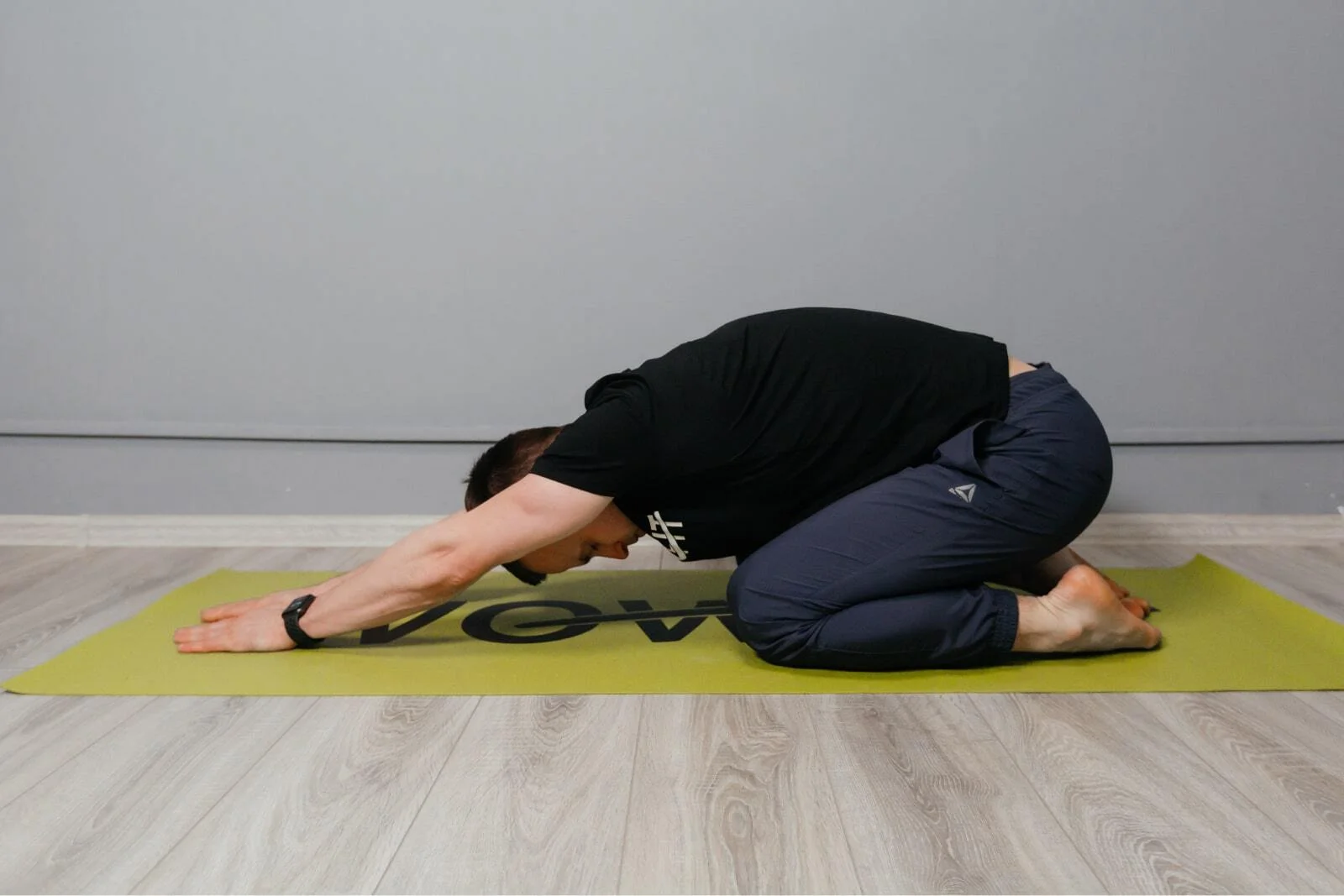 Man resting in child's pose on a yoga mat