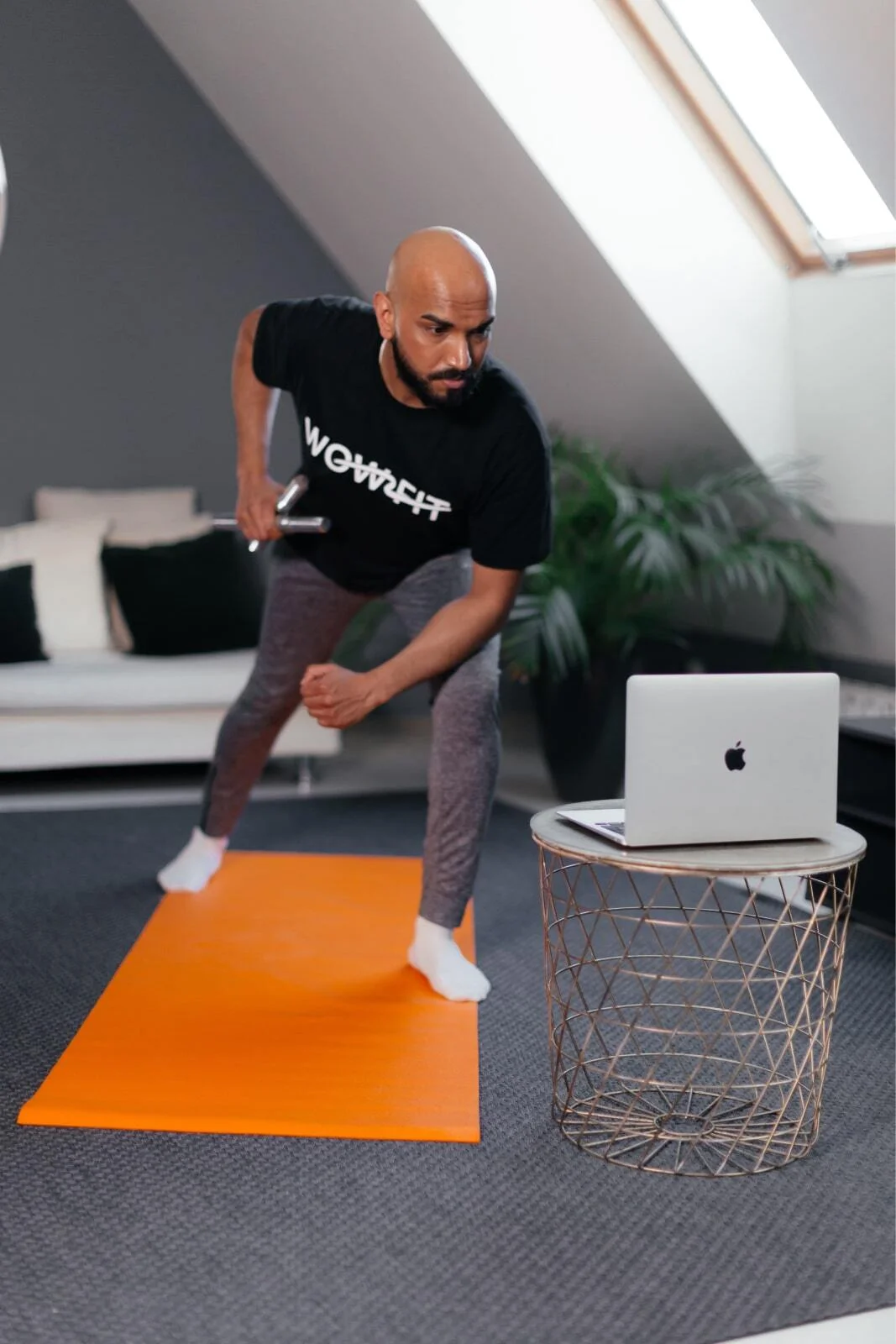 Man exercising at home in front of a laptop during an online training session