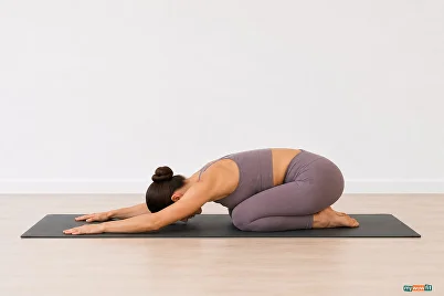Woman resting in child's pose on a yoga mat