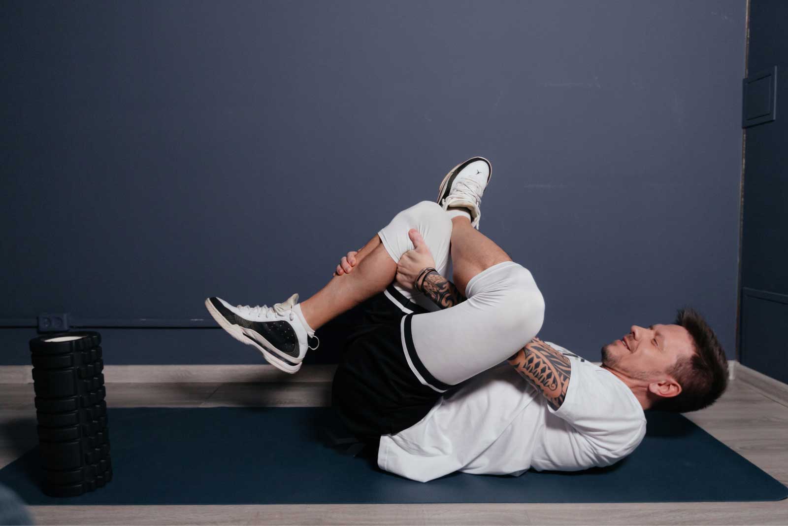 Man doing a lying glute stretch on a mat at home