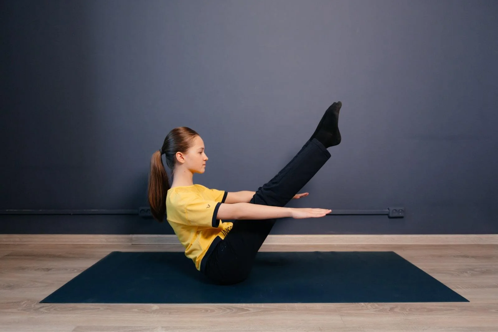 Woman doing a V-sit core exercise on a mat